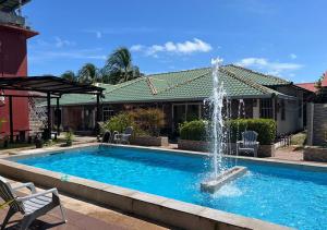 a swimming pool with a fountain in front of a house at D'Lima Beach Inn in Pantai Cenang