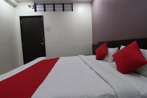 a bedroom with a large bed with red pillows at Hotel O Shri Sai Niwara Lodge in Dhule