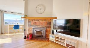 a living room with a fireplace and a tv at StayAU 2BR Home with Stunning Views in Tasmania in Inveresk