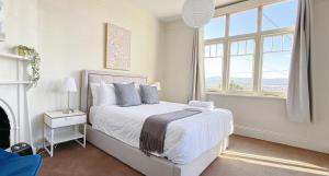 a white bedroom with a bed and a window at StayAU 2BR Home with Stunning Views in Tasmania in Inveresk