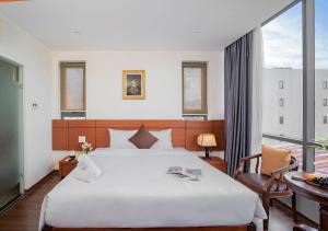 a bedroom with a large white bed and a balcony at Quoc Cuong Center Da Nang Hotel by Haviland in Danang +87 photos