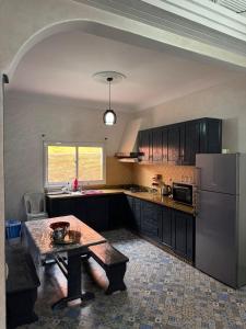 a kitchen with a table and a stainless steel refrigerator at Elegant Seaside Retreat 80m from Beach, Pool & BBQ in Aghroude