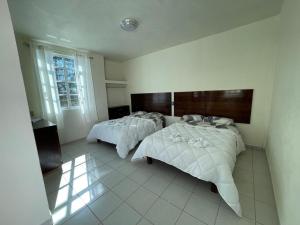 a bedroom with two beds and a window at Hotel Leilani in San Andrés Sinaxtla