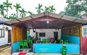 a pavilion with green tables and chairs and a television at Golden Kudle Beach Resort in Gokarna