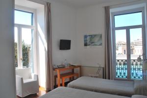 a bedroom with a bed and a chair and a window at L'Approdo delle Sirene in Syracuse