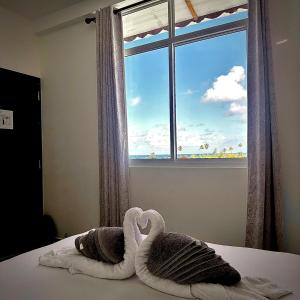 a bedroom with two swan towels on a bed with a window at KANBULO House Maldives in Huraa +7 photos