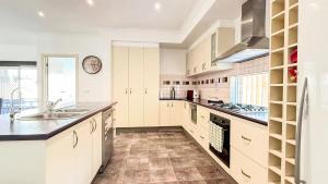 a kitchen with white cabinets and a sink and a stove at StayAU Family Haven Pet-Friendly Caroline Springs in Caroline Springs
