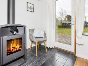 a fireplace in a room with a chair and a window at 6 person holiday home in Nibe in Nibe