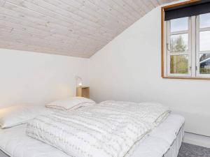 a white bed in a white room with a window at 6 person holiday home in Nibe in Nibe