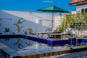 a swimming pool with a table and an umbrella at Maggiez Leisure Home Dodoma in Dodoma