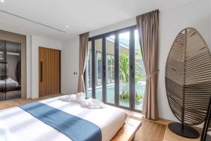 een slaapkamer met een bed en een groot raam bij V253 Brand New 2BR with Pool and Full Kitchen in Thalang +58 foto's