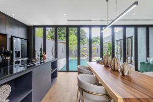 een keuken en eetkamer met een lange tafel en stoelen bij V253 Brand New 2BR with Pool and Full Kitchen in Thalang