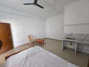 Habitación blanca con cama y escritorio. en Kuniya Arcade Stay, en Kasaragod