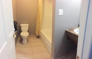 a bathroom with a toilet and a tub and a sink at Motel L'Escale in Chambord +6 photos
