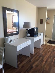 Habitación con escritorio blanco, TV y espejo. en Motel L'Escale, en Chambord