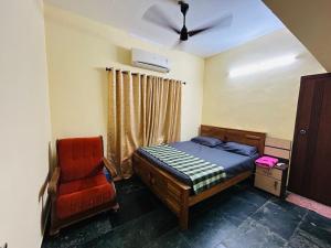 una camera da letto con un letto e una sedia di Bluebell Homes A - 3 BHK Near to Calicut a Beypore