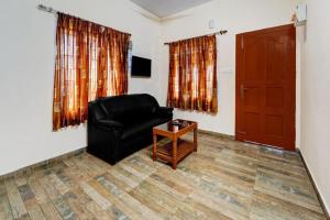a living room with a black leather chair and a table at Kodai Mist with Pick up & Drop in Kodaikānāl +7 photos