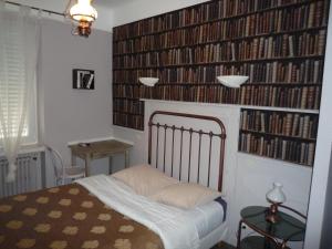 
a bedroom with a bed, bookshelf and a lamp at Hotel Du Centre in Hagondange
