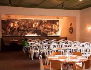 a dining room with white chairs and tables and a painting at Western Hotel Ballarat in Ballarat