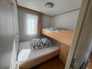 two bunk beds in a small room with a window at Chalet op Ameland voor 5 personen in Buren