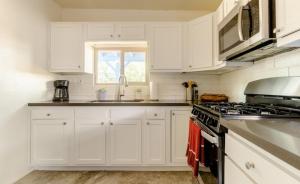 a kitchen with white cabinets and a stove top oven at Central House with Pool & Hot Tub in Tucson +7 photos