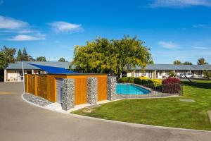 a tiny house with a pool and a fence at Cherylea Motel in Blenheim