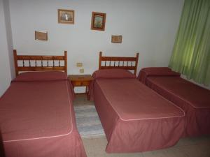 two beds with red covers in a room at Pensión Versalles in Algeciras