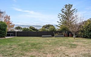 a yard with two benches and a fence at StayAU Newly Luxe 6BR Cradle Mountain with fireplace in Kings Meadows