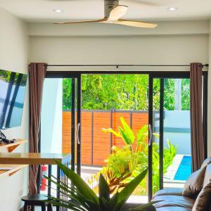 ein Wohnzimmer mit einer großen Glasschiebetür mit einer Terrasse in der Unterkunft Villa Kokini in Koh Samui