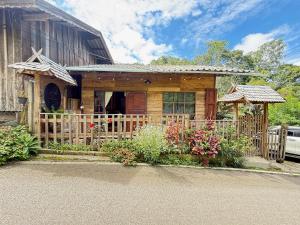 a small wooden house with a fence and flowers at Poka-Homestay in Ban Pok Nai
