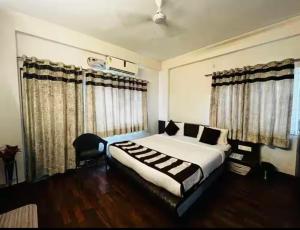 ボーパールにあるHotel Smriti Grandのベッドルーム1室(ベッド1台、椅子、窓付)