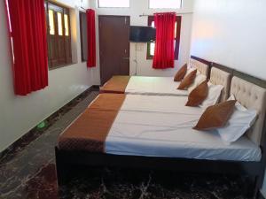 two beds in a room with red curtains at daulatvilass by Grandview mansionhotel in Udaipur