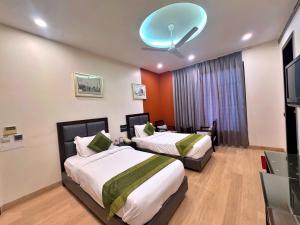 a bedroom with two beds and a flat screen tv at Amber Inn by Orion Hotels in New Delhi