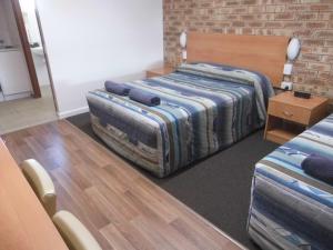 a room with two beds and a brick wall at Nanango Fitzroy Motel in Nanango