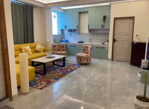 a living room with a couch and a table and a kitchen at The Refuge Inn in Lakhwār
