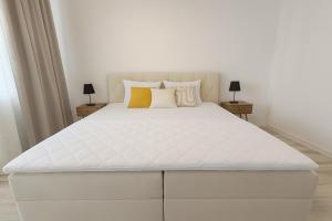 a white bed in a white bedroom with two lamps at Family Apartman Michalovce in Michalovce