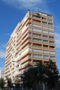um edifício alto com árvores em frente em Apartamentos Concorde em Alicante