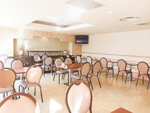 a conference room with tables and chairs and a screen at Tetora Higashimuroran in Muroran