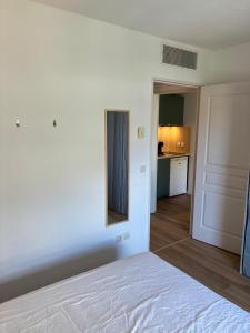 a bedroom with a white bed and a kitchen at Le 302, T2 confortable dans Résidence bien située in Grasse