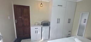 Una cocina con gabinetes blancos y un refrigerador. en 28 Tambotie avenue, en Klerksdorp