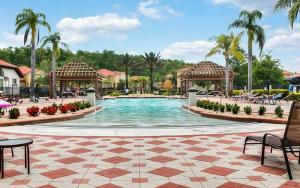 a swimming pool at a resort with chairs and palm trees at Luxury 12BR Home w Pool Theater Game Room in Kissimmee