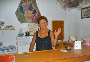 a woman standing behind a counter in a room at Arian Hotel in Parikia