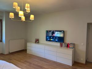 a living room with a television on a white dresser at Maison spacieuse entre lacs et montagnes in Les Mollettes