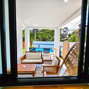 eine Terrasse mit Stühlen, einer Couch und einem Tisch in der Unterkunft Villa Kokini in Koh Samui
