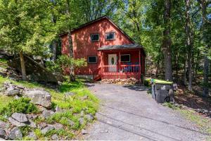 a red cabin in the middle of a forest at Cozy 3Br Fire Pit Hammock 2 Minutes to Beach in East Stroudsburg