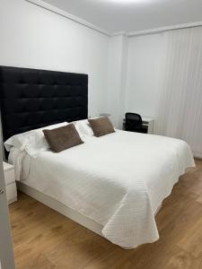 a bedroom with a large white bed with a black headboard at Apartamento Castro Holidays - con Parking incluido in Castro-Urdiales