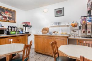 a kitchen with wooden cabinets and tables and chairs at Travelodge by Wyndham Grants Pass in Grants Pass