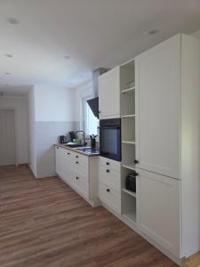 una cucina con mobili bianchi e un piano di lavoro di Ferienbungalow mit 2 Schlafzimmern, Sauna & Whirlpool a Wernigerode