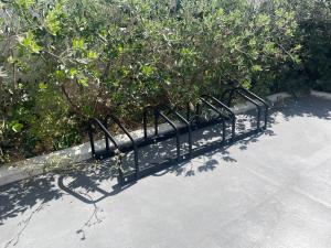 a black metal bench on a sidewalk next to bushes at Casa Quetta in Bari