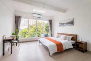 a bedroom with a bed and a desk and a window at Glow House Sukhumvit 54, Spacious Modern Rooms near BTS On Nut in Bangkok